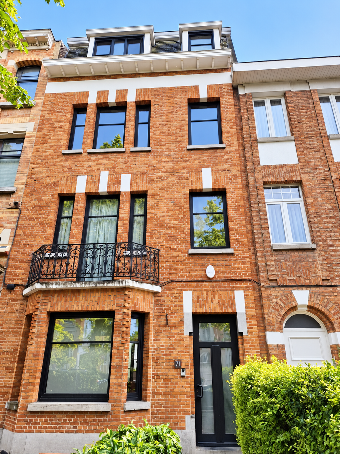 Façade urbaine en briques rouges, châssis de fenêtres noirs